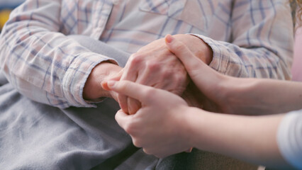 Loving daughter holding wrinkled hands of senior mother, taking care, comforting
