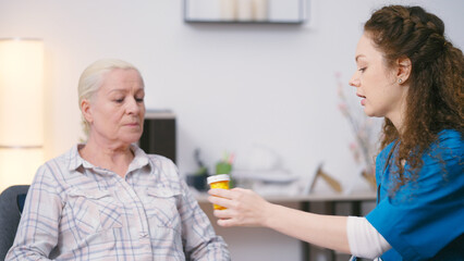 Friendly woman practitioner prescribing medication to mature patient, home care - obrazy, fototapety, plakaty