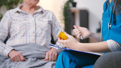 Female therapist prescribing vitamins or dietary supplements to a senior patient - obrazy, fototapety, plakaty