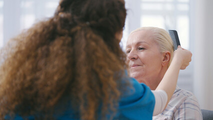 Nurse combing senior woman's hair, living in a nursing home, private care