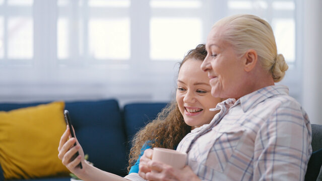 Woman volunteer helping senior lady with a video call on smartphone, home care
