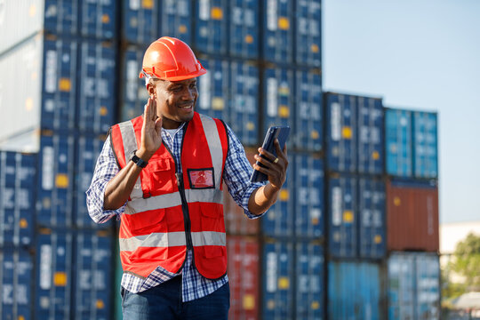 African factory worker or engineer holding tablet and video call to someone in containers warehouse storage