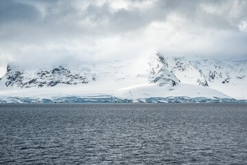 Aerial view of a mountainous terrain covered in a gleaming blanket of fresh white snow in Antarctica