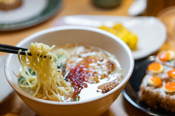 Hand with chopsticks takes noodles of ramen soup. Traditional Asian cuisine