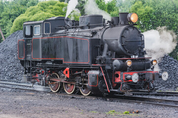 Fototapeta na wymiar Retro steam locomotive stands near depot.