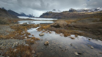 Breathtaking landscape featuring snow-capped mountains and a glacier with rocky outcroppings