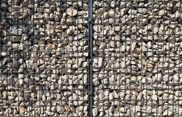 Wire gabion fence filled with small white brownish stones. Background and texture.	