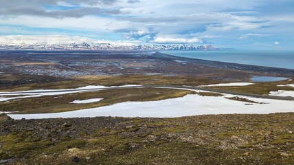 Tranquil landscape featuring a snow-covered field with a small lake in the background