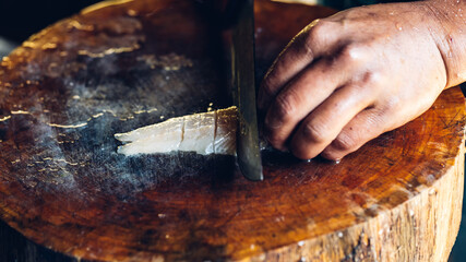 The sturgeon is in the hands of the experienced chef. He is using a knife to slice sturgeon fillet for sashimi and sushi. A chef cutting a sturgeon fillet with a knife on a cutting board.