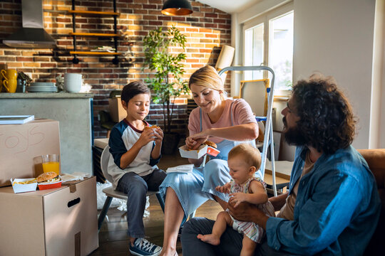 Young caucasian family having fast food and burgers after moving in their new home apartment