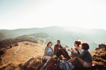 Young diverse group of female friends having a coffee break after hiking in the hills and mountains