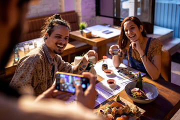 Waiter taking a photo with a smart phone of a young couple on a date in a sushi restaurant