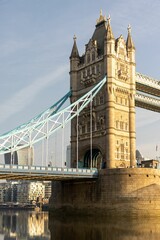 a tower bridge spanning over a river in the sun,