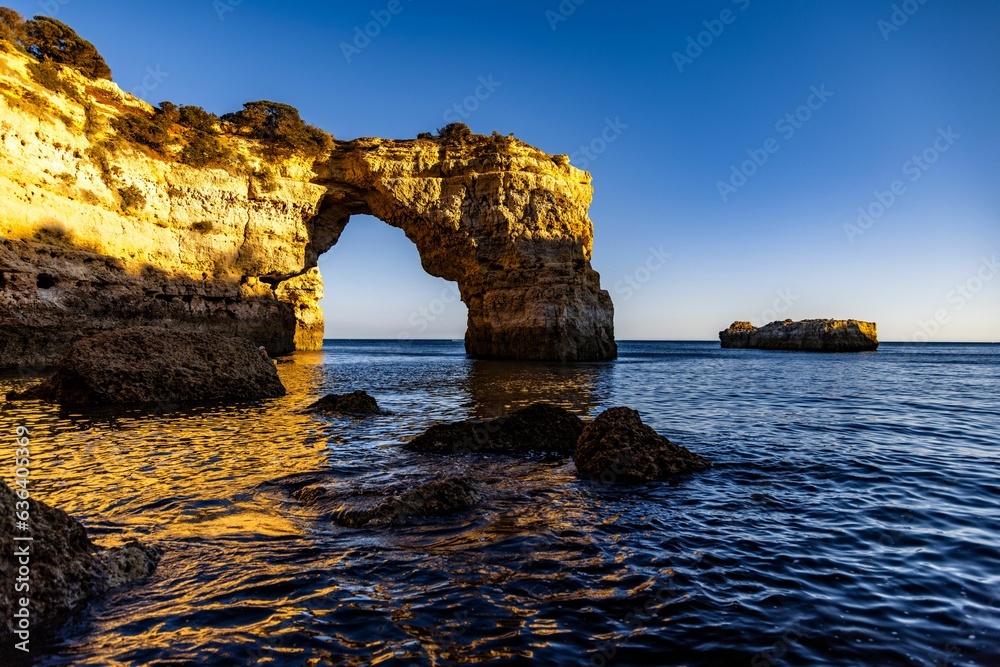 Sticker scenic view of rocky formations on the coastline against the sea at golden hour