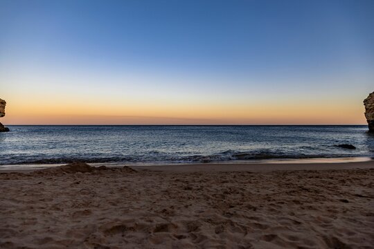 Scenic view of a sandy beach against the sea at sunset