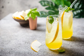 Melon juice, lemonade in glasses with ice and melon slices garnished with basil leaves. Concept of fresh summer drink