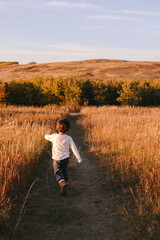 Young boy walking down a footpath through a field in Autumn