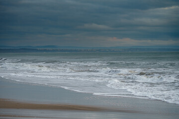 Scenic shot of foamy ocean waves crashing on each other on a foggy day