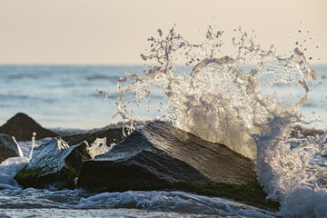 Beautiful shot of a moment of splash made while the water hitting a big rock in the sea © Hristo Anestev/Wirestock Creators