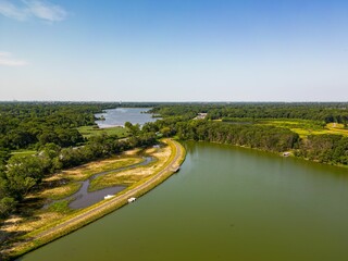 Fototapeta premium Aerial top down view over a park with a green pond on a sunny day on Long Island, NY