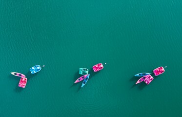 Aerial view of vibrant pedal boats, floating on the tranquil, crystal clear ocean