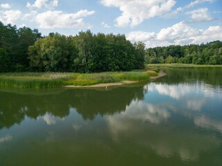 Obraz premium a river with green grass and trees in the background and sky and clouds