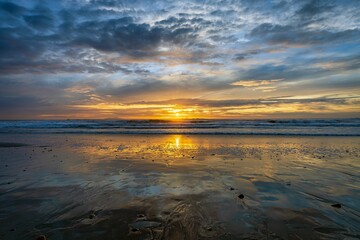 Calm ocean during the low tide in Oxnard California with the golden sunset shining in the background