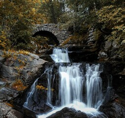 Stunning view of a waterfall cascading down rocks under a bridge
