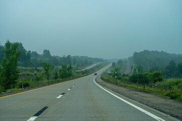 Fototapeta premium Scenic view of a long empty highway winding through a lush forest with tall trees
