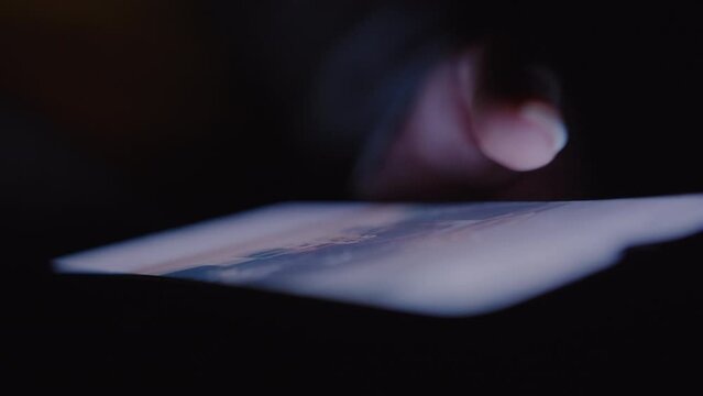 Digital Nightfall: Woman's Hand Scrolling Social Media Feed on Phone in the Darkness