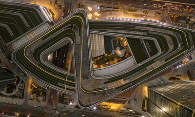 Aerial view of a busy city intersection at night with multiple cars driving along roads