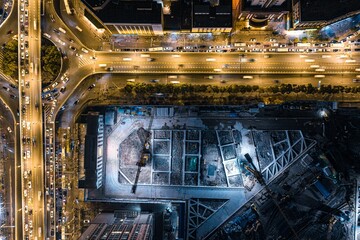 Nighttime aerial view of a roundabout filled with cars and illuminated buildings in the background