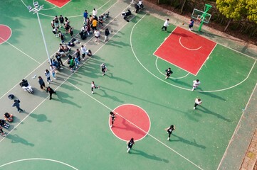 an aerial shot of a group of children playing basketball outside