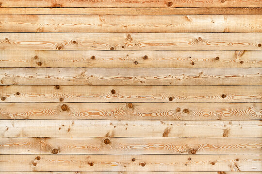 Texture of the wall made of knotty sanded wooden boards with multiple cracks as a retro natural background