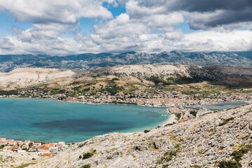 Obraz premium Small coastal town with urban buildings near the turquoise water and hills