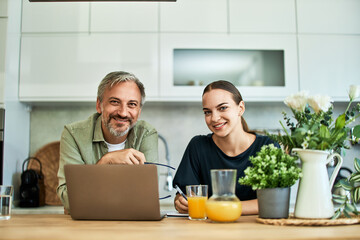 Portrait of a senior male and adult female freelancers working together on a laptop.