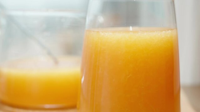 A glass of orange juice with pulp, against the backdrop of the sun and a pitcher of juice.