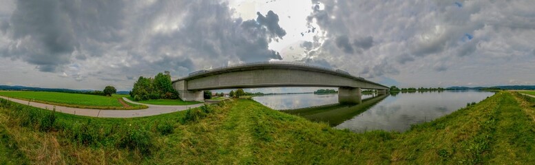 Panoramic landscape of a bridge over a lake in the green field