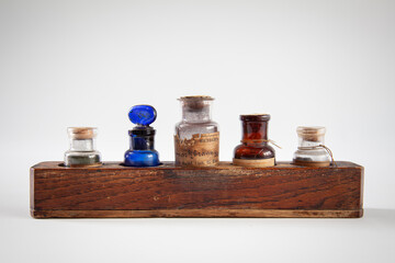 A set of antique glass or crystal jars on a wooden stand, containing chemicals for various uses. 