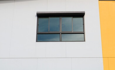 Glass windows rectangle shape with window tint film and white painted wall of building, mirror image of sky and cloud on glass window.