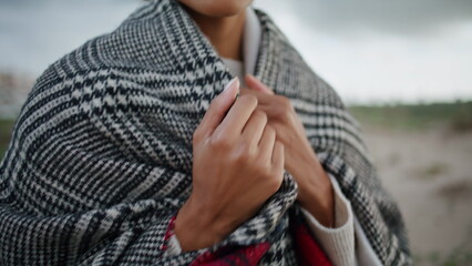 Closeup woman chest walking windy beach. African american hands adjusting scarf