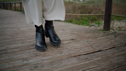 Autumn boots walking wooden path closeup. Calm traveler legs strolling walkway