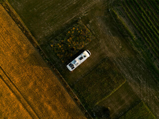 Obraz premium Camper Bus auf einem Feld, Top-down, Sonnenuntergang
