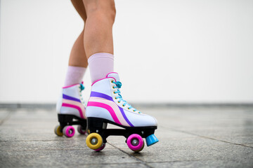 Cropped photo of female legs in colorful vintage roller skates shoes isolated on white wall...