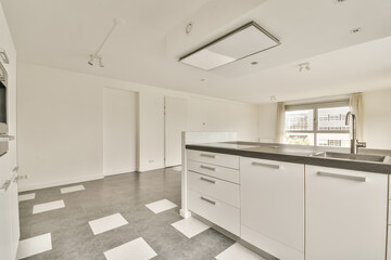 an empty kitchen with white cabinets and black counter tops on the floor in front of the door is a window