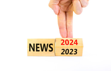 2024 News new year symbol. Businessman turns a wooden cube and changes words News 2023 to News 2024. Beautiful white table white background, copy space. Business 2024 news new year concept.