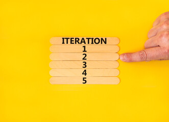 Time to iteration 2 symbol. Concept word Iteration 1 2 3 4 5 on wooden sticks. Businessman hand. Beautiful yellow table yellow background. Business planning and time to iteration 2 concept. Copy space