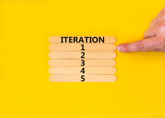 Time to iteration 1 symbol. Concept word Iteration 1 2 3 4 5 on wooden sticks. Businessman hand. Beautiful yellow table yellow background. Business planning and time to iteration 1 concept. Copy space