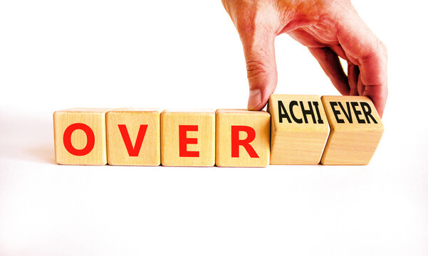 Achiever or overachiever symbol. Businessman turns wooden cubes and changes word Achiever to Overachiever. Beautiful white background. Business achiever or overachiever concept. Copy space.