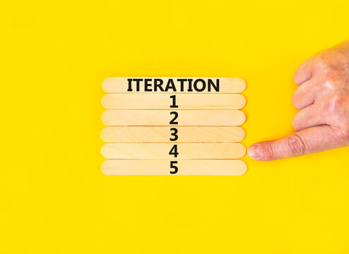 Time to iteration 4 symbol. Concept word Iteration 1 2 3 4 5 on wooden sticks. Businessman hand. Beautiful yellow table yellow background. Business planning and time to iteration 4 concept. Copy space
